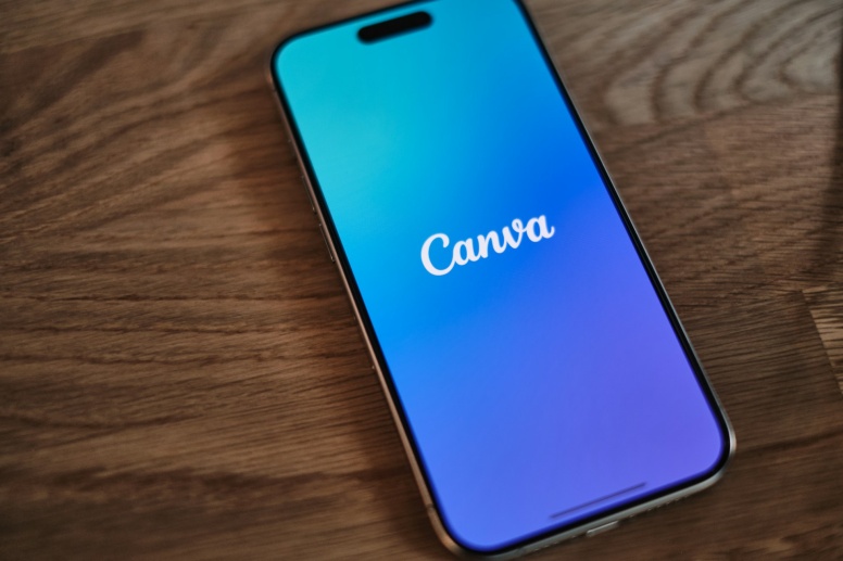 phone with the canva logo on the display on a wooden surface